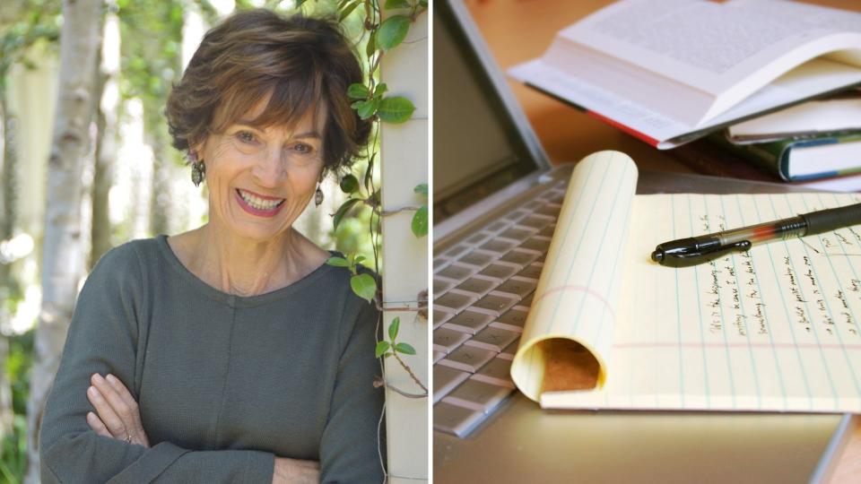 Suzanne McCourt smiles while leaning on a wall with ivy, pen and paper with writing on it, laptop. 