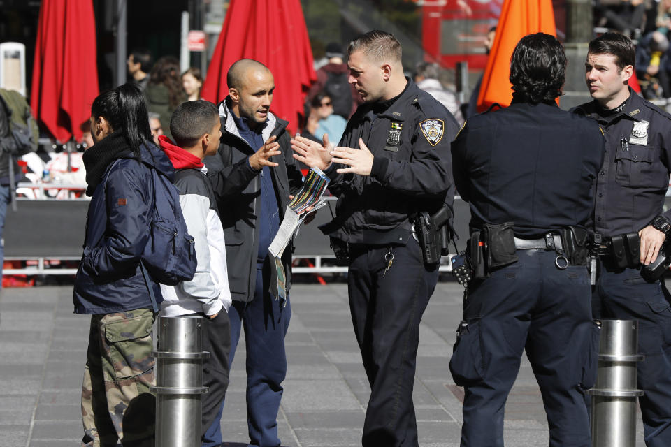 A New York City Police Department officer assists a person in New York's Times Square, Friday, Oct. 19, 2018. New reforms aimed at improving police interactions in New York City include requirements that officers hand out their business cards to people they stop and explain why law enforcement activity is taking place. (AP Photo/Richard Drew)