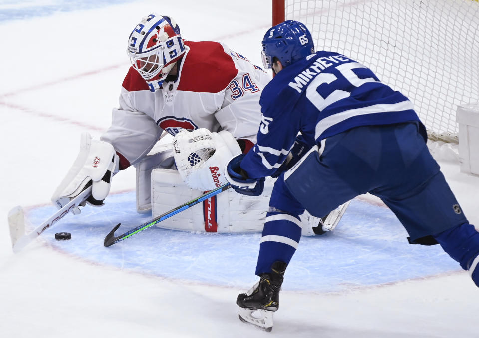 Montreal Canadiens goaltender Jake Allen (34) makes a save as Toronto Maple Leafs forward Ilya Mikheyev (65) looks for the rebound during the second period of an NHL hockey game Saturday, May 8, 2021, in Toronto. (Nathan Denette/The Canadian Press via AP)