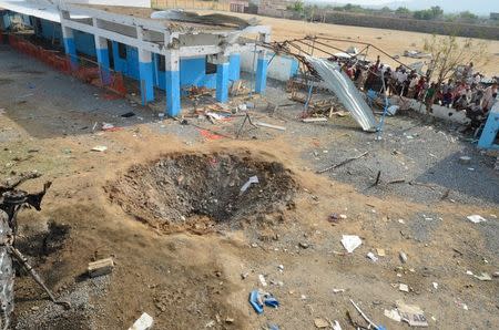 People look at a crater caused by a Saudi-led coalition air strike at the yard of a hospital operated by Medecins Sans Frontieres in the Abs district of Hajja province, Yemen August 16, 2016. REUTERS/Abduljabbar Zeyad