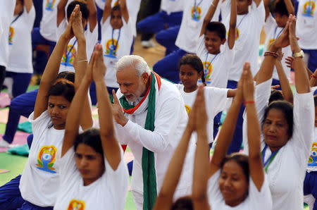 Prime Minister Narendra Modi (C) speaks with a participant as they perform yoga during a camp to mark the International Day of Yoga, in New Delhi, June 21, 2015. REUTERS/Adnan Abidi