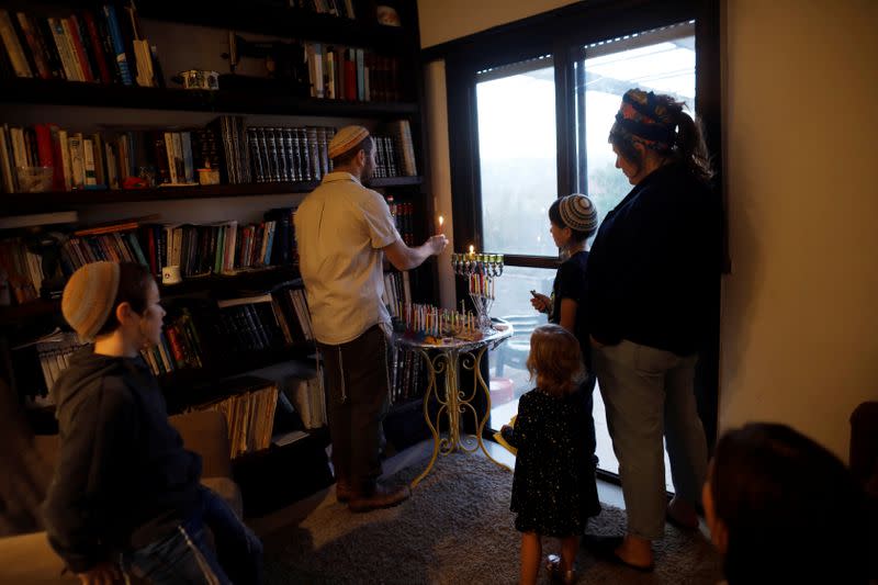 The Orbach family lights a hanukkiyah, a candlestick with nine branches that is lit to mark Hanukkah, the 8-day Jewish Festival of Lights, at their home in the Jewish settlement of Tekoa, in the Israeli-occupied West Bank