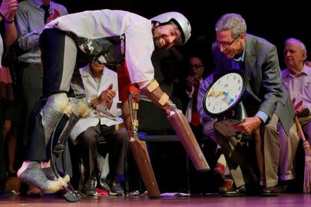 Nobel Laurette Eric Maskin (R) presents the 2016 Ig Nobel Prize in Biology to Thomas Thwaites of the United Kingdom for "creating prosthetic extension of his limbs that allowed him to move in the manner of, and spend time roaming the hills in the company of, goats" during the 26th First Annual Ig Nobel Prize ceremony at Harvard University in Cambridge, Massachusetts, U.S. September 22, 2016. REUTERS/Brian Snyder