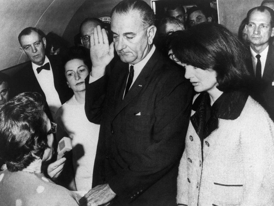 Vice President Lyndon B. Johnson is sworn in to the office of the Presidency aboard Air Force One in Dallas, Texas, hours after the assassination of President John F. Kennedy. Johnson is flanked by wife, Lady Bird Johnson (L), and First Lady Jacqueline Kennedy during the ceremony