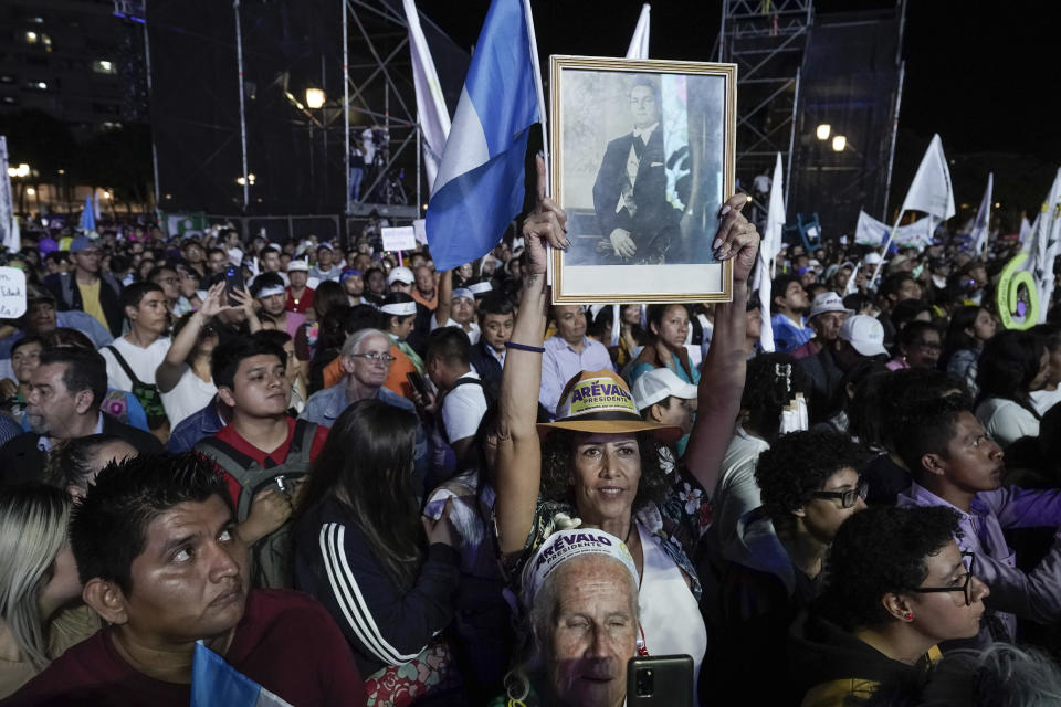 FILE - Supporters hold a photo of former Guatemalan President Juan Jose Arevalo as they listen to his son Bernardo, current presidential candidate with the Seed Movement party, during his closing campaign rally at Constitution Square in Guatemala City, Aug. 16, 2023. Arevalo faces rival and former first lady Sandra Torres, the National Unity of Hope, UNE, presidential candidate, in the Sunday, Aug. 20 runoff election. (AP Photo/Moises Castillo, File)