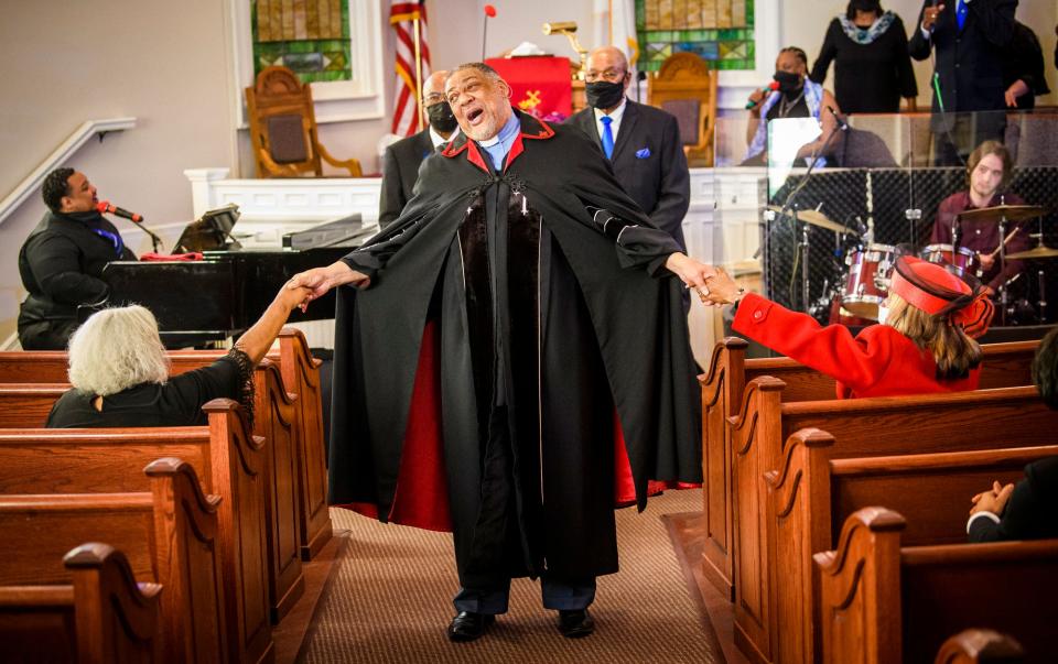 Rev. Bruce Rose holds the hands of Tamara Ramey-Carter, left, and Ester Jones, right, during Sunday's service at Second Baptist Church.