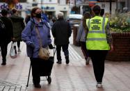 A council worker wearing a safety vest marked 'social distancing champion' walks through the town centre following the outbreak of the coronavirus disease (COVID-19) in Wrexham, Britain