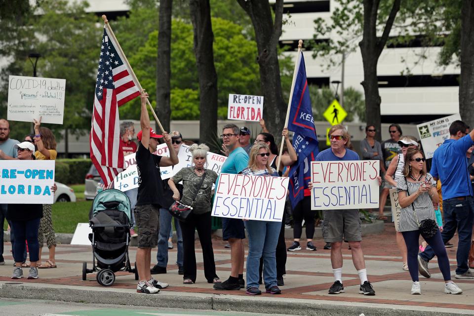 Protesters demanding Florida businesses and government reopen, march in downtown Orlando, Fla., Friday, April 17, 2020. Small-government groups, supporters of President Donald Trump, anti-vaccine advocates, gun rights backers and supporters of right-wing causes have united behind a deep suspicion of efforts to shut down daily life to slow the spread of the coronavirus.