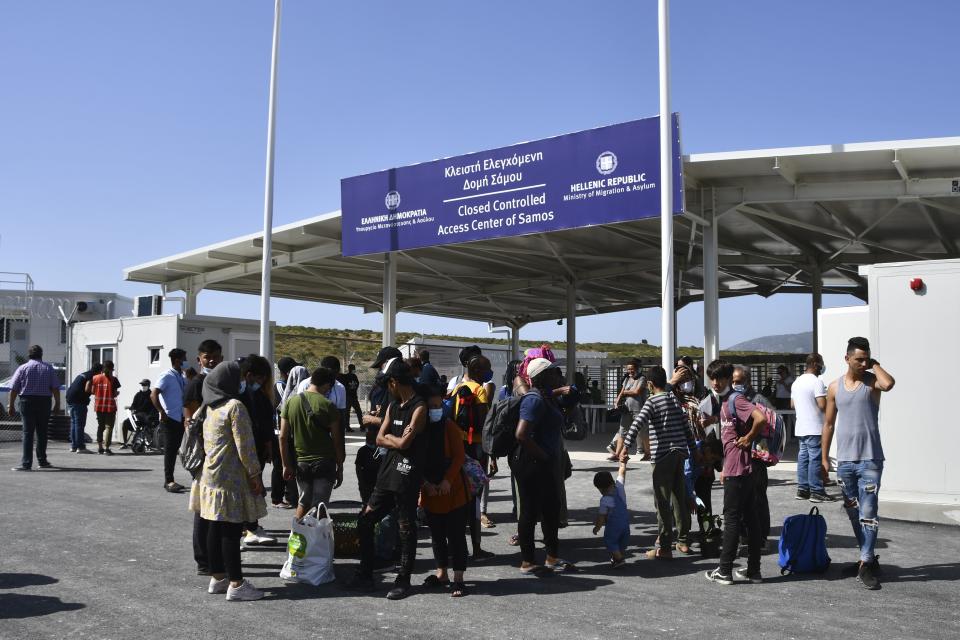 Migrants wait outside the new closed monitored facility in Zervou village, on the eastern Aegean island of Samos, Greece, Monday, Sept. 20, 2021. The transfer of the migrants to the new, €43 million ($50 million) facility began Monday and be completed by Wednesday. (AP Photo/Michael Svarnias)