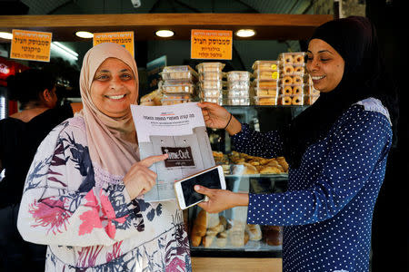 Arab-Israeli women hold a copy of "Time Out Ramallah", a special edition of the Time Out magazine marking 50 years since Israel's occupation of the West Bank and Gaza Strip, distributed to them by employees of "Time Out Tel Aviv", in Jaffa, Israel October 26, 2017. REUTERS/Amir Cohen