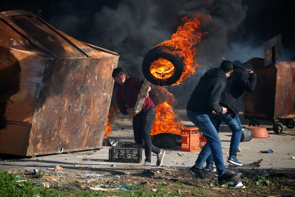 A Palestinian uses a piece of wood to move a burning tire during clashes with Israeli troops in Ramallah, near the settlement of Beit El, in the occupied West Bank: ABBAS MOMANI/AFP/Getty Images