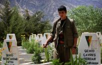 A member of the Kurdistan Workers' Party (PKK) walks past graves at a cemetary on July 29, 2015 deep in the Qandil mountain, the PKK headquarters in northern Iraq