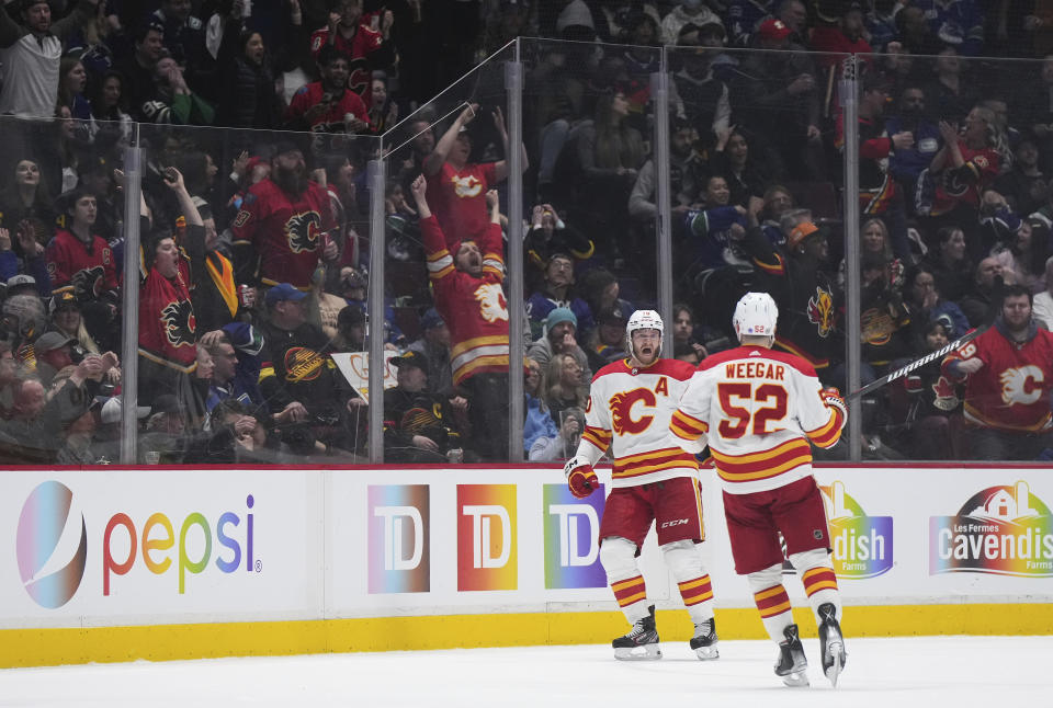 Calgary Flames' Jonathan Huberdeau, back, and MacKenzie Weegar celebrate Huberdeau's goal against the Vancouver Canucks during the third period of an NHL hockey game Friday, March 31, 2023, in Vancouver, British Columbia. (Darryl Dyck/The Canadian Press via AP)