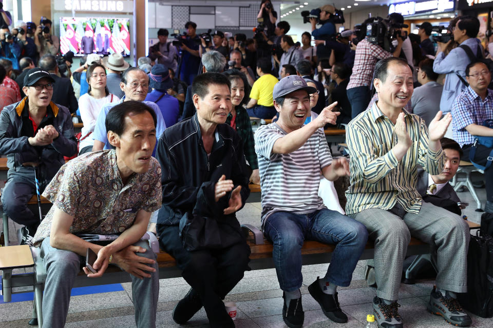 Some people&nbsp;applaud as they watch live footage of the summit from a train station in Seoul.