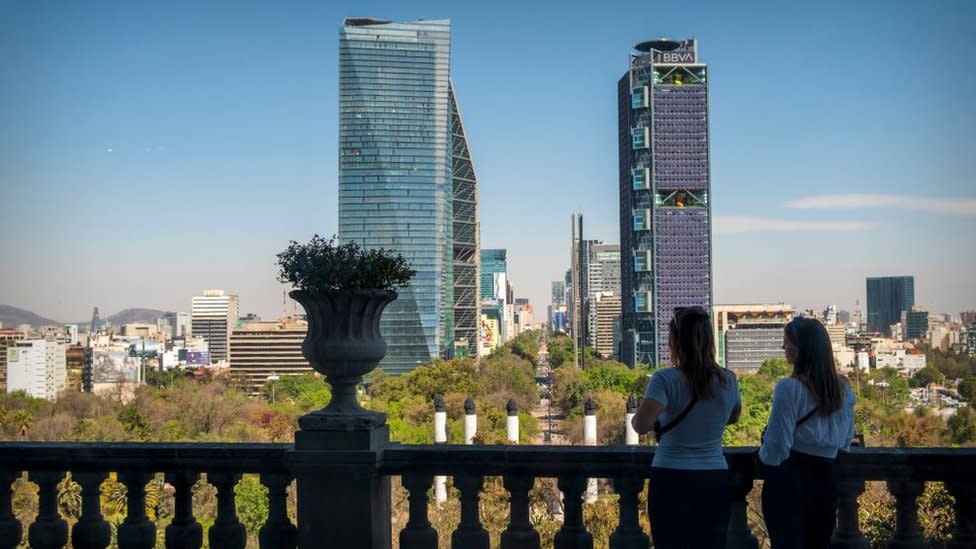 Dos mujeres de espalda mirando hacia el Castillo de Chapultepec y el Paseo de la Reforma en la distancia, Ciudad de México, México.