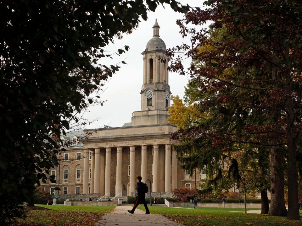 People walk by Old Main on the Penn State University main campus on Nov. 9, 2017 in State College, Pa.