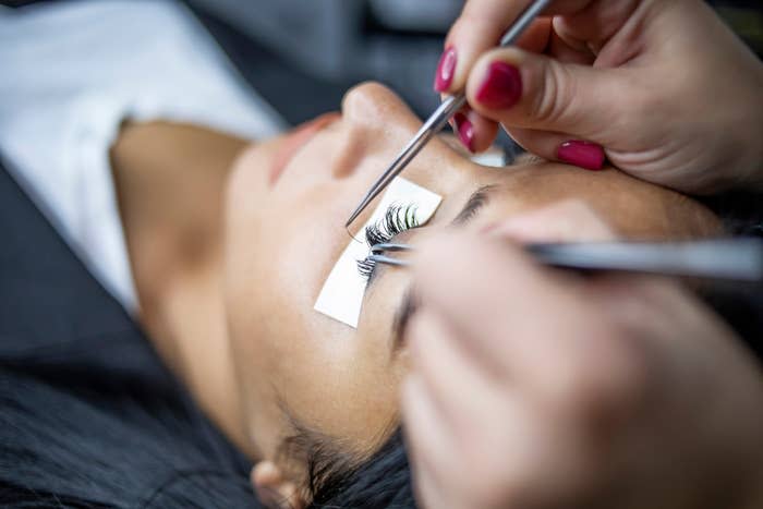 Close-up of a person receiving eyelash extensions applied by a technician