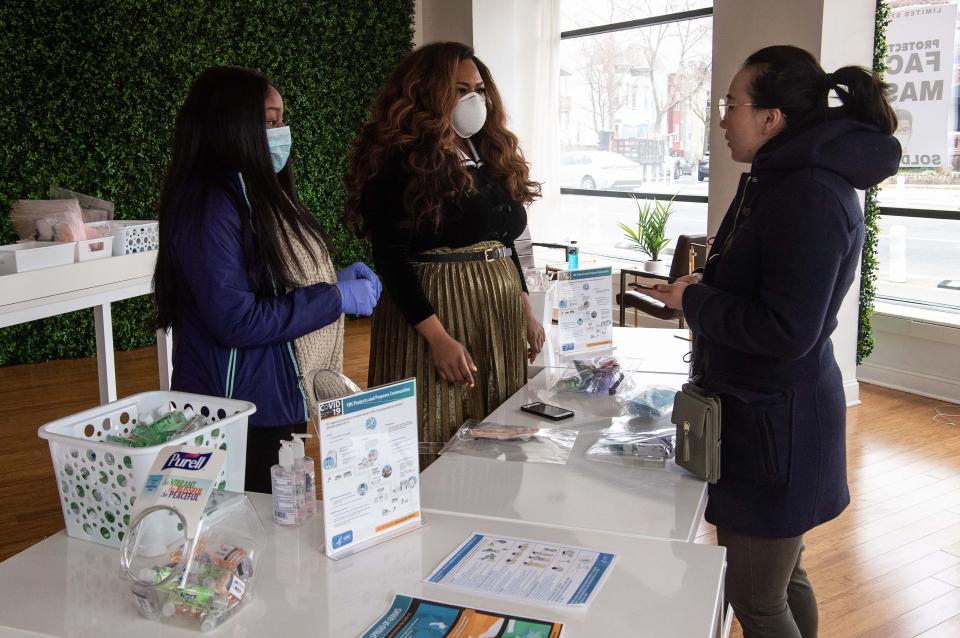 Adilisha Patrom (C) and her assistant (L) speak to a customer in her coronavirus pop-up store in Washington, DC, on March 6, 2020. - As supplies of face masks and hand sanitizer have dwindled due to the outbreak of Covid-19, Adilisha Patrom, owner of the Suites DC, a co-working and event space, who had bought a stock of face masks for her father who is suffering from cancer, decided to share her trove with the community. US lawmakers passed an emergency  USD 8.3 billion spending bill to combat the coronavirus on Thursday as the number of cases surged in the country's northwest and deaths reached 12. Since then the toll has risen to 12 and the virus has spread to at least 15 states -- the latest being Maryland adjacent to the nation's capital Washington. (Photo by NICHOLAS KAMM / AFP) (Photo by NICHOLAS KAMM/AFP via Getty Images)