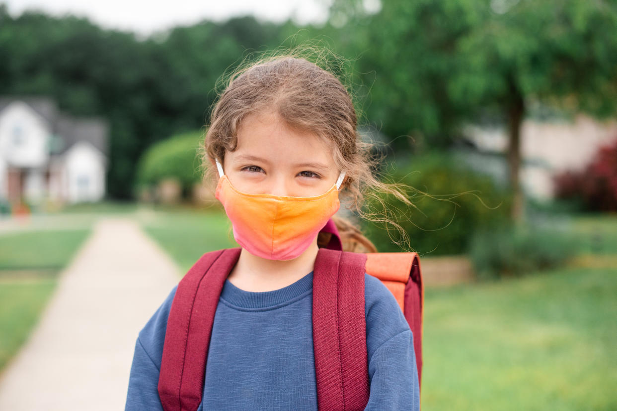Caucasian little girl ready to go to school wearing a face mask
