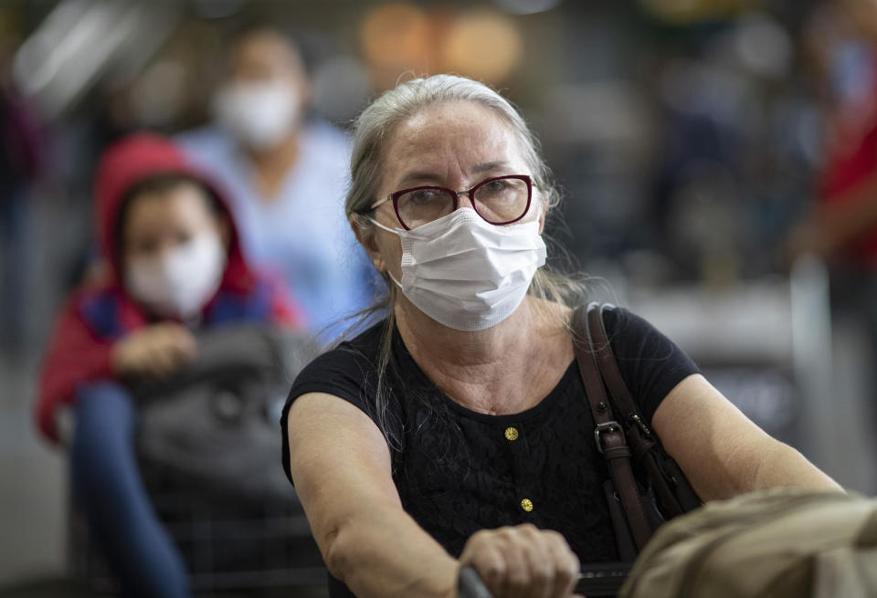 Passengers wear masks as a precaution against the spread of the new coronavirus COVID-19 as they arrive to the Sao Paulo International Airport in Sao Paulo, Brazil, Thursday, Feb. 27, 2020. (AP Photo/Andre Penner)