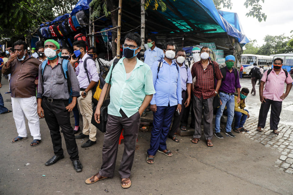 People wearing face masks wait for transport outside a bus station in Kolkata, India, Friday, Aug. 14, 2020. India's coronavirus death toll overtook Britain's to become the fourth-highest in the world with another single-day record increase in cases Friday. (AP Photo/Bikas Das)