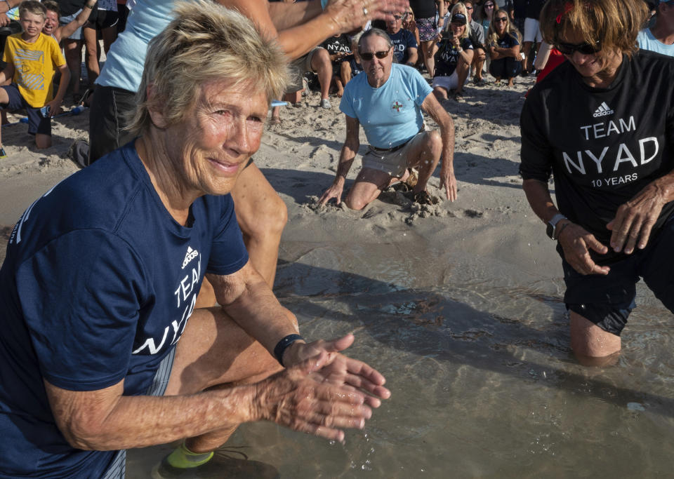 In this photo provided by the Florida Keys News Bureau, Diana Nyad, left, is emotional after helping to release "Rocky," a rehabilitated green sea turtle, into the Atlantic Ocean Sunday, Oct. 22, 2023, from a beach in Key West, Fla. "Rocky's" release was part of a weekend 10th anniversary celebration commemorating Nyad's successful 2013 swim from Cuba to Key West, ending at the same beach. Rescued in January and transported to the Florida Keys-based Turtle Hospital, "Rocky" required an eight-hour intestinal surgery, breathing treatments, a blood transfusion and months of medications to survive. In 2013, at age 64, Nyad swam continuously for 52 hours and 54 minutes across the Florida Straits from Havana to the island city. Bonnie Stoll, Nyad's expedition leader, is at right. (Andy Newman/Florida Keys News Bureau via AP)