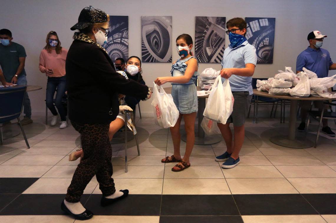 Lucia Franyie, 10, center, hands out a meal to Hazel Quintero during a Thanksgiving meal distribution event for senior residents at Smathers Plaza II organized by the Kiwanis Club of Little Havana in Miami, Florida, on Thursday, Nov. 26, 2020.