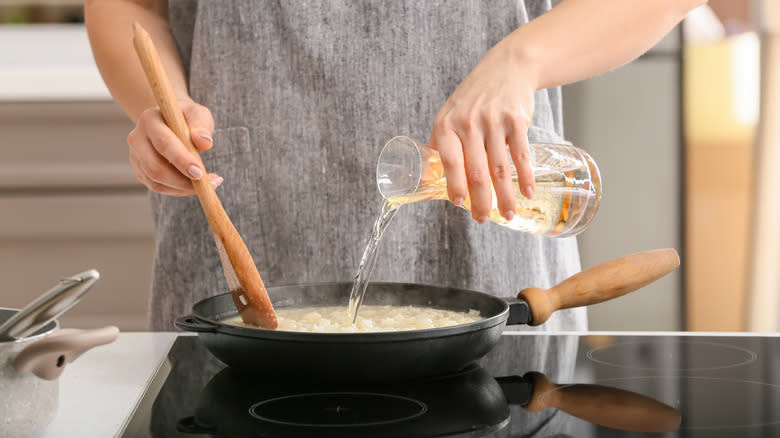 woman adding wine to food