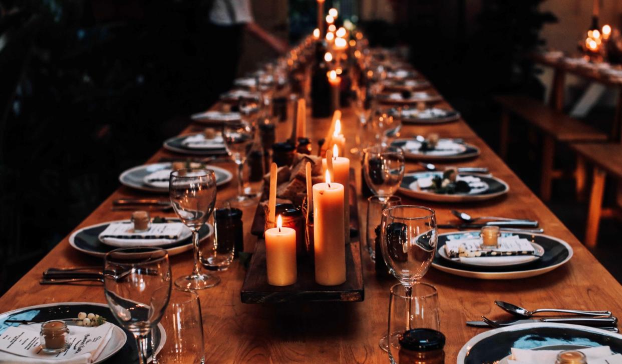  A long table decorated with plates, glasses and candles. 