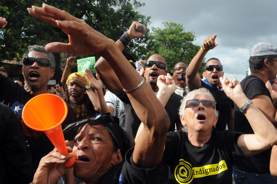 Dominicans shout slogans during a demonstration against the fiscal reform in Santo Domingo, Dominican Republic, Sunday, Nov. 11, 2012. Hundreds of Dominicans protested against the government of Danilo Medina who presented to Congress the disputed tax legislation as a way to help close the $4.6 billion deficit in the government's budget. The measure will increase the general sales tax to 18 percent from 16 percent, will raise the price of gasoline and impose taxes on basic food products. (AP Photo/Manuel Diaz)