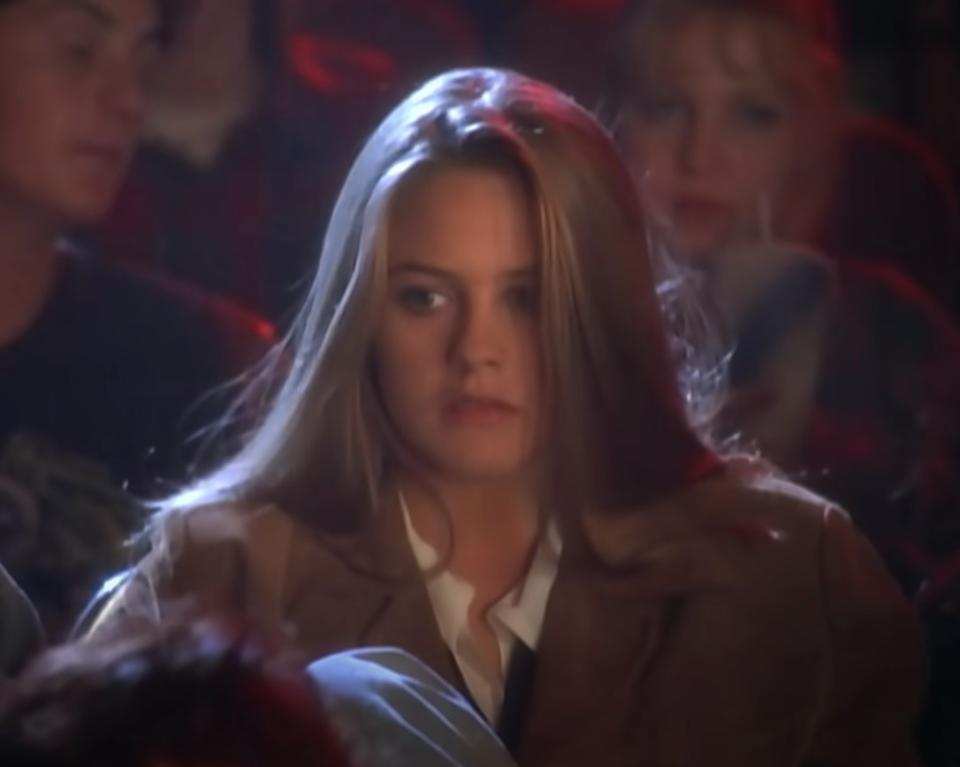 Alicia Silverstone sits in a movie theater as she acts in the "Cryin'" music video