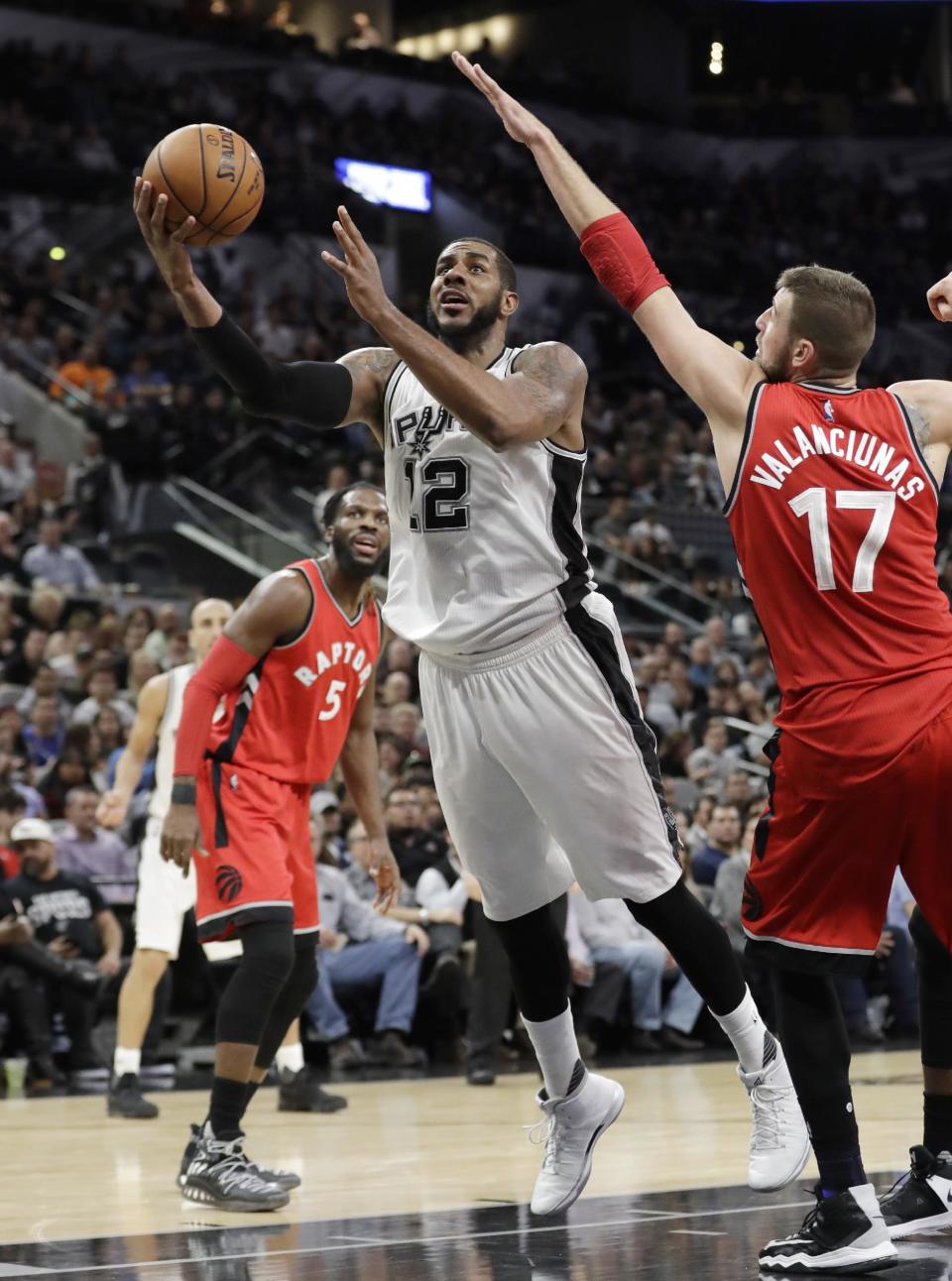 San Antonio Spurs forward LaMarcus Aldridge (12) shoots around Toronto Raptors center Jonas Valanciunas (17) during the second half of an NBA basketball game, Tuesday, Jan. 3, 2017, in San Antonio. San Antonio won 110-82.(AP Photo/Eric Gay)