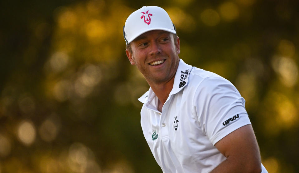   Gooch smiles while wearing a white top with LIV logos on it  