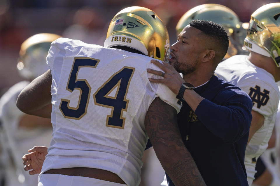 FILE - Notre Dame head coach Marcus Freeman talks with offensive lineman Blake Fisher (54) before an NCAA college football game against Clemson Saturday, Nov. 4, 2023, in Clemson, S.C. With Notre Dame’s Marcus Freeman and Michigan's Sherrone Moore following similar paths, there is excitement that having Black faces in the most visible position at blue blood programs is becoming normalized and that young Black coaches finally are being viewed as the rising stars. (AP Photo/Jacob Kupferman, File)