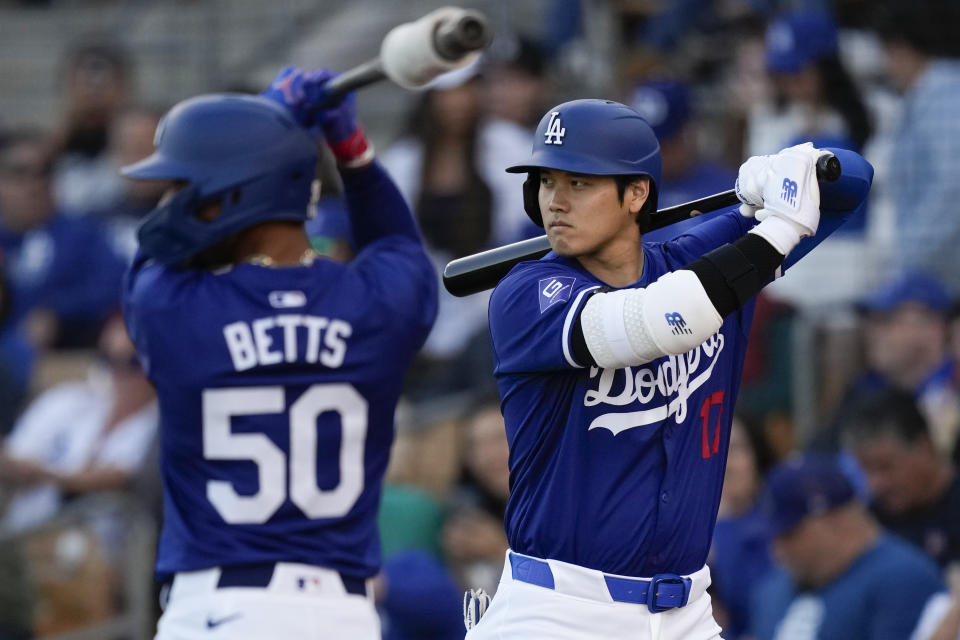 Los Angeles Dodgers' Mookie Betts (50) and Shohei Ohtani warm up on deck before a spring training baseball game against the Cincinnati Reds on Friday, March 8, 2024, in Phoenix. The game was canceled because of rain. (AP Photo/Carolyn Kaster)