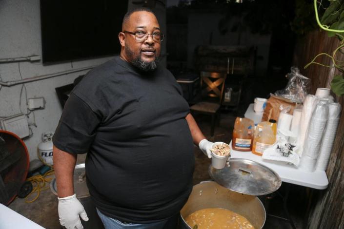 Larry D Reaves, 53, owner of World’s Famous Souseman BBQ, serves a cup of his world famous pork souse in the backyard of his Opa-locka home in Florida on Saturday, Nov. 19, 2022.