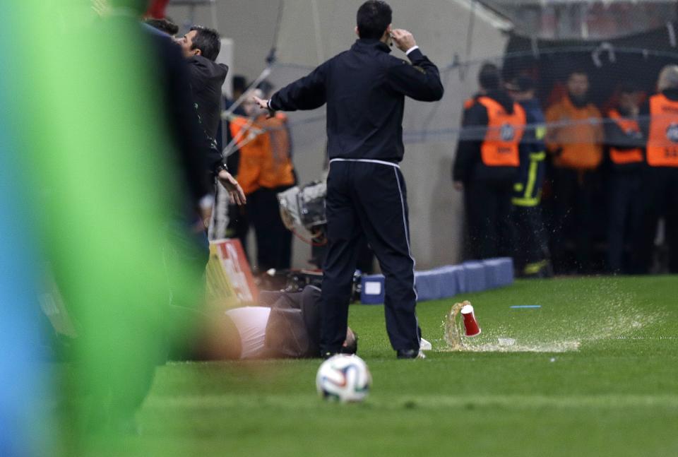 Panathinaikos' coach Giannis Anastasiou lays on the grass after being hit by a plastic cup during a Greek League soccer match against Olympiakos at Georgios Karaiskakis stadium, in Piraeus port, near Athens, on Sunday, March 2, 2014. (AP Photo/Thanassis Stavrakis)