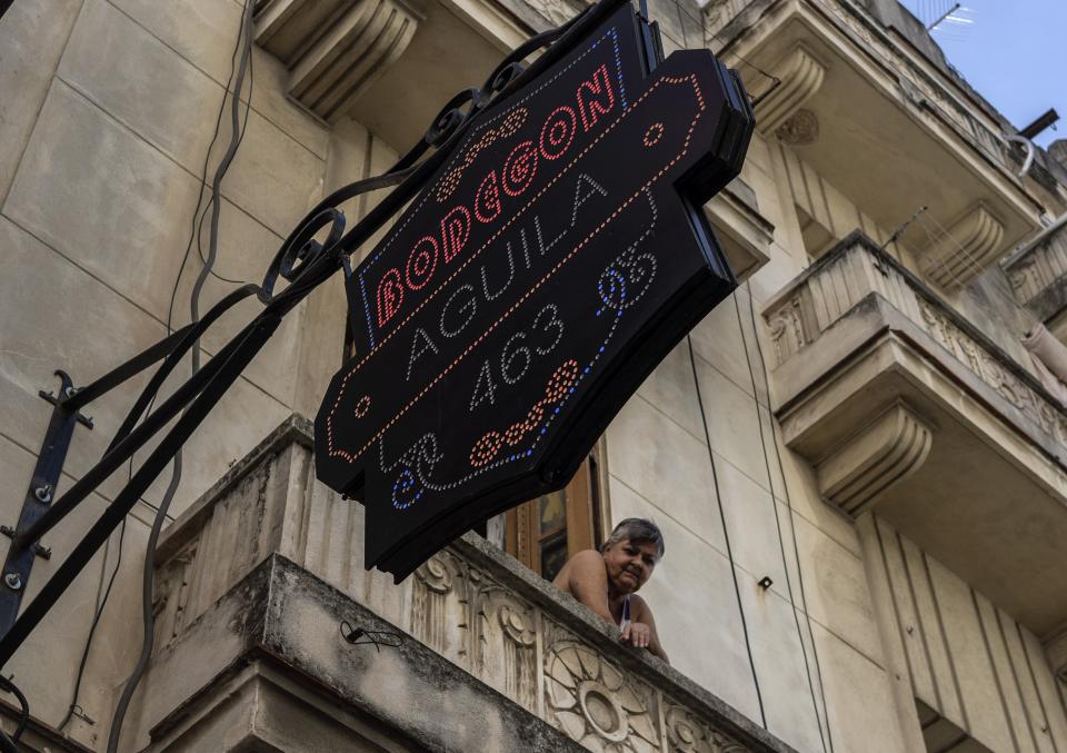 A resident looks out from her balcony over a private grocery store in Havana, Cuba, Saturday, Nov. 11, 2023. Dozens of tiny grocery stores have sprung up around Cuba in recent months, referred to locally as “mipymes” — pronounced MEE-PEE-MEHS, offering many products not available elsewhere and usually operate out of private homes or garages. (AP Photo/Ramon Espinosa)