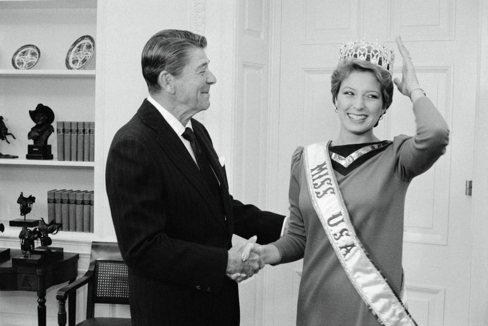 Miss USA Terri Lee Utley smiles as she shakes President Ronald Reagan's hand and adjusts her tiara.