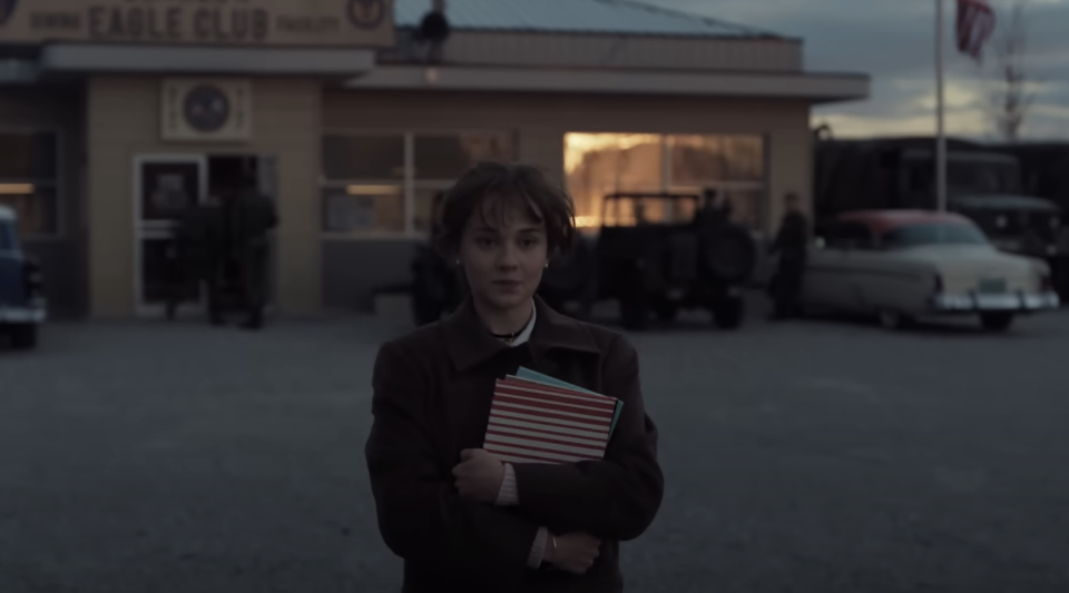 Priscilla in the movie, holding several notebooks