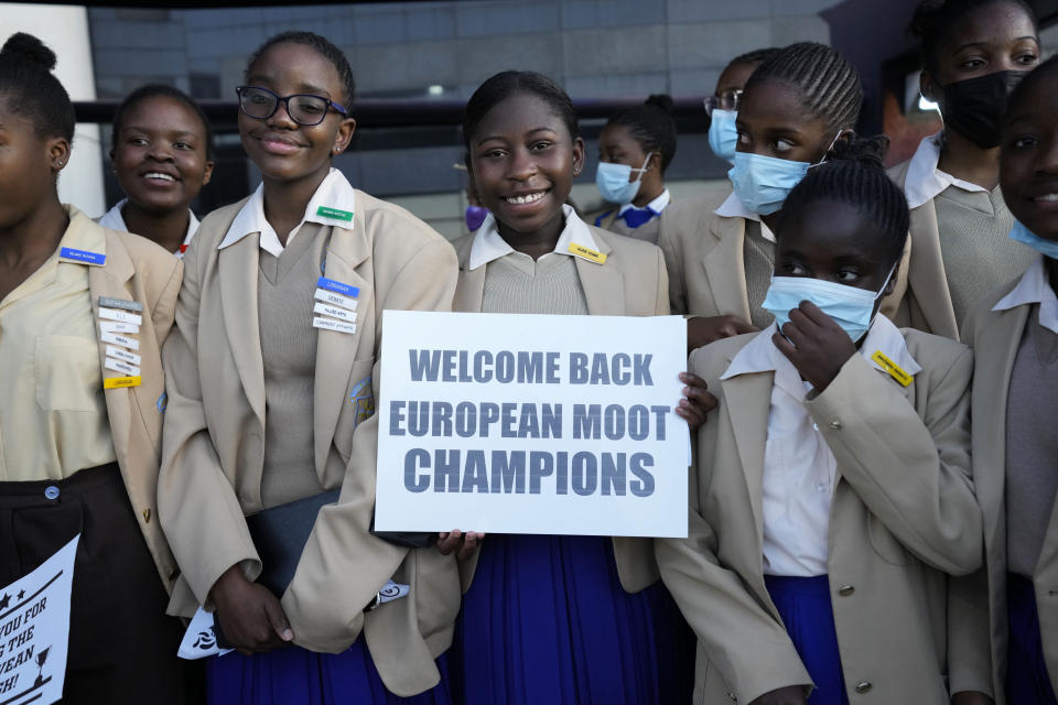 Schoolchildren line up with placards to welcome Zimbabwean high school World and European moot court competition champions as they arrive back at the Robert Mugabe International airport in Harare, Thursday, July, 7, 2022. A history-making team of Zimbabwean high school students that became world and European moot court competition champions has been widely praised in a country where the education system is beset by poor funding, lack of materials and teachers’ strikes. (AP Photo/Tsvangirayi Mukwazhi)