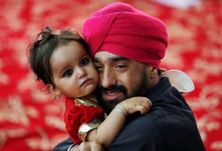 An Afghan Sikh holds his child inside a Gurudwara, or a Sikh temple, during a religious ceremony in Kabul, Afghanistan June 8, 2016. REUTERS/Mohammad Ismail