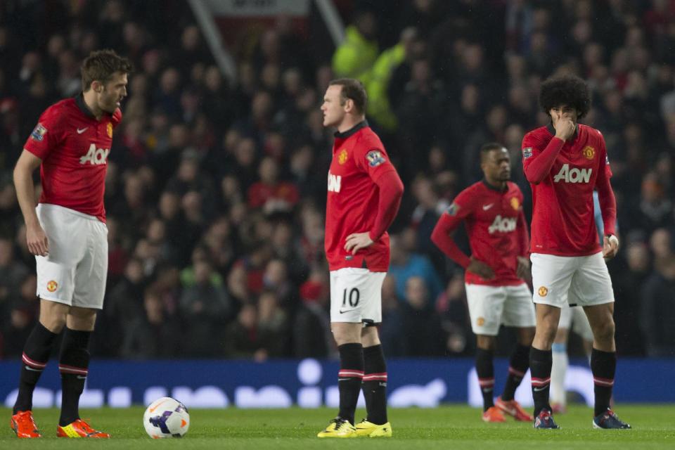 Manchester United players including Marouane Fellaini, right, Wayne Rooney, centre and Michael Carrick wait for play to restart after an early goal by Manchester City's Edin Dzeko, out of frame, during their English Premier League soccer match at Old Trafford Stadium, Manchester, England, Tuesday March 25, 2014. (AP Photo/Jon Super)