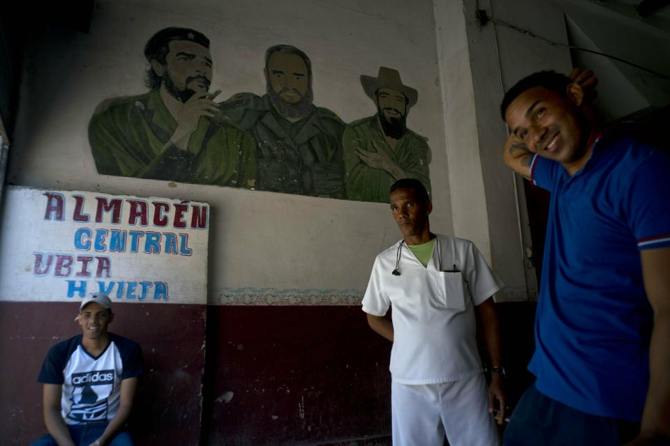 Men take a break inside a warehouse featuring a mural of revolutionary leaders Camilo Cienfuegos, right, Ernesto "Che" Guevara, left, and Fidel Castro, in Havana, Cuba, Wednesday, April 17, 2019. Shortages are so severe that ordinary Cubans and the country’s highest leaders are openly referring to the “special period,” the years of economic devastation and deep suffering that followed the collapse of the Soviet Union, Cuba’s Cold War patron. (AP Photo/Ramon Espinosa)