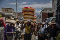 FILE - In this June 5, 2021, file photo, a man carries goods at a street market in Port-au-Prince, Haiti. In Haiti, hospitals are turning away patients as the country awaits its first shipment of vaccines. A major delivery via COVAX was delayed amid government concern over side effects and a lack of infrastructure to keep the doses properly refrigerated. (AP Photo/Joseph Odelyn, File)