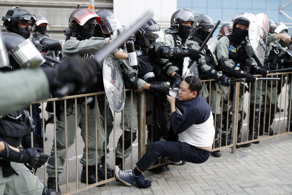 Riot policemen detain a pro-democracy protester during a rally in Hong Kong, Sunday, Dec. 1, 2019. A huge crowd took to the streets of Hong Kong on Sunday, some driven back by tear gas, to demand more democracy and an investigation into the use of force to crack down on the six-month-long anti-government demonstrations. (AP Photo/Vincent Thian)