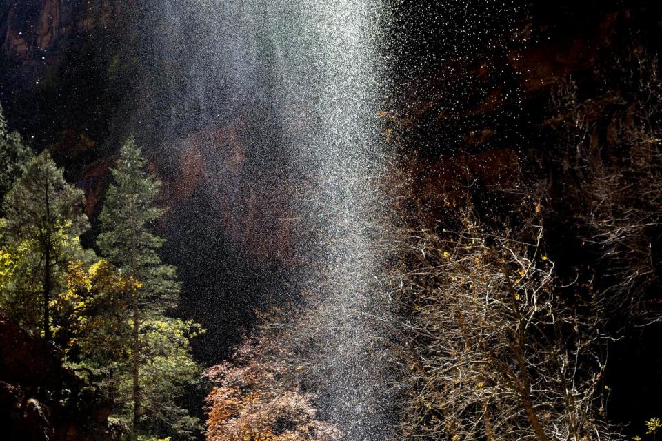 A glowing curtain of water flows off a cliff into Lower Emerald Pool