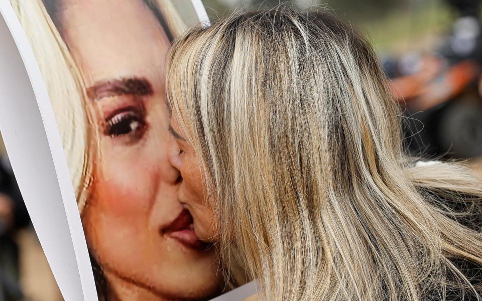 A woman kisses a picture of Mercedes Oria Amar who was killed at the site of the Nova festival