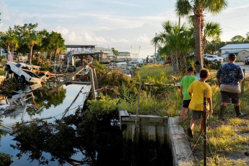 The Rollison brothers Landon, 17, Lawton, 12, and Lane, 11, walk past a canal littered with debris after the arrival of Hurricane Idalia in their hometown of Horseshoe Beach, Florida on August 31, 2023 (REUTERS)