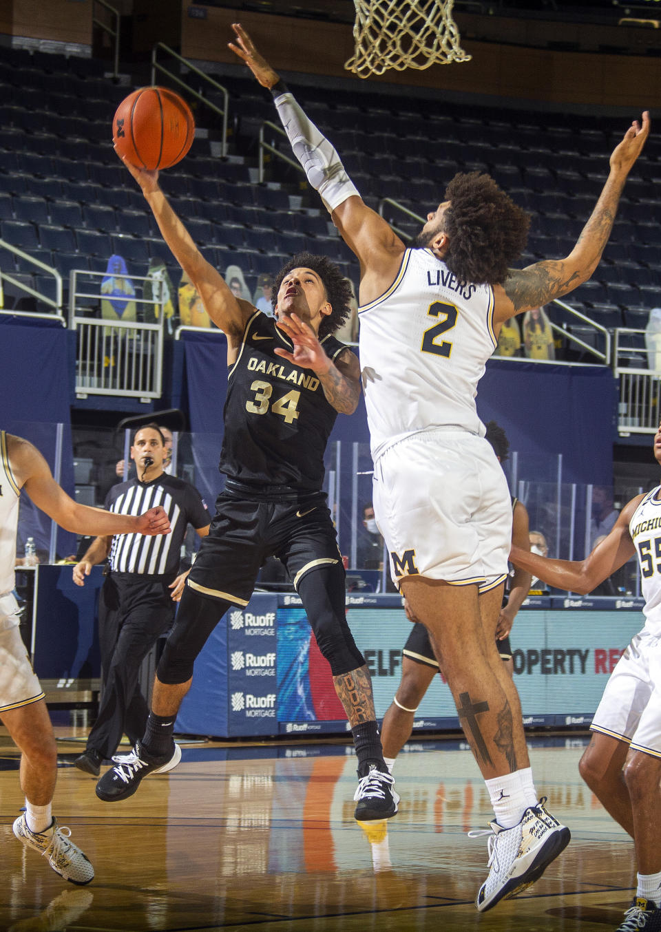 Oakland guard Jalen Moore (34) attempts a basket while defended by Michigan forward Isaiah Livers (2), in the first half of an NCAA college basketball game at Crisler Center in Ann Arbor, Mich., Sunday, Nov. 29, 2020. (AP Photo/Tony Ding)